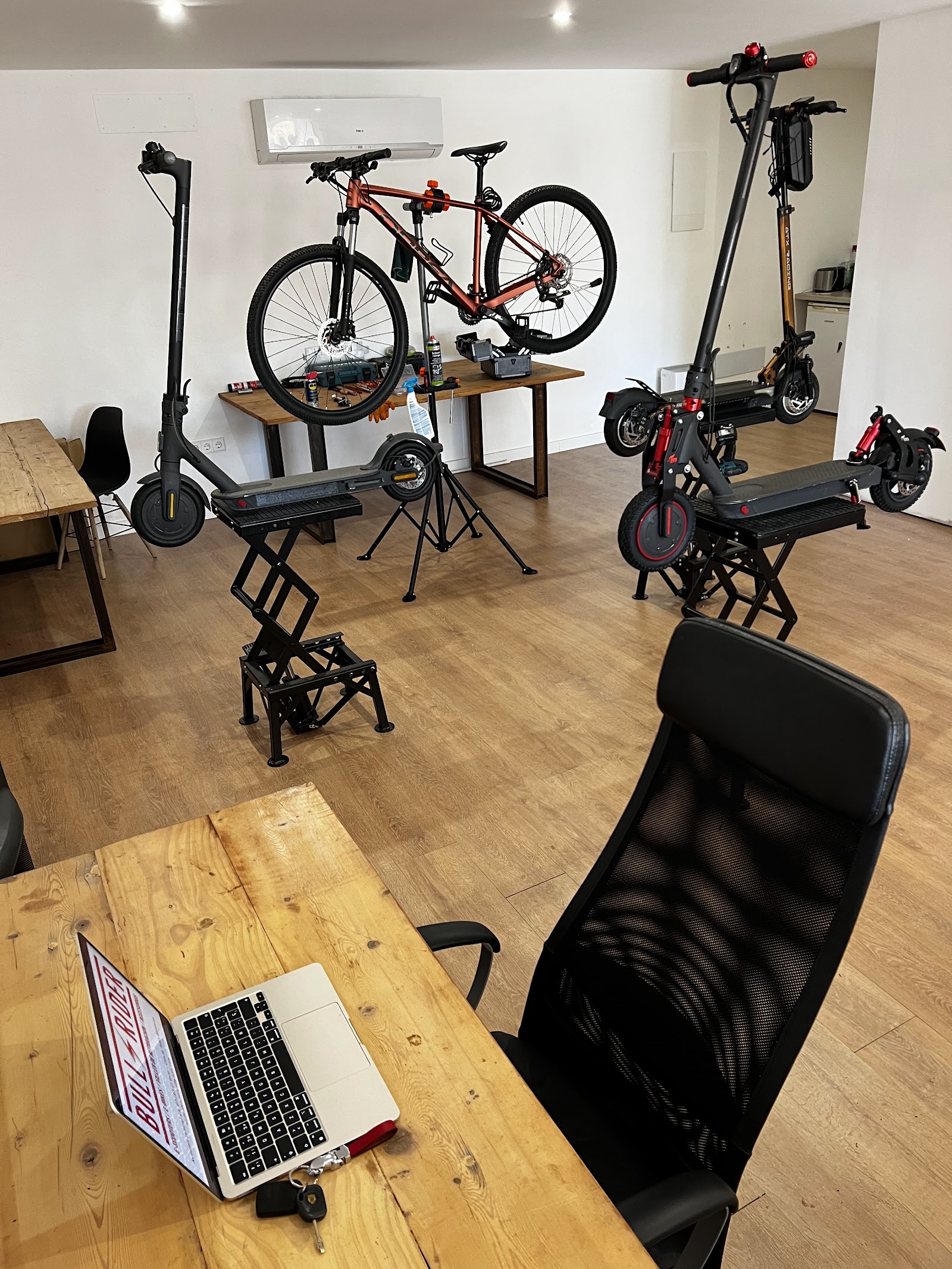 Taller de BULLRIDER con patinetes en elevadores y una bicicleta en el soporte de reparación
